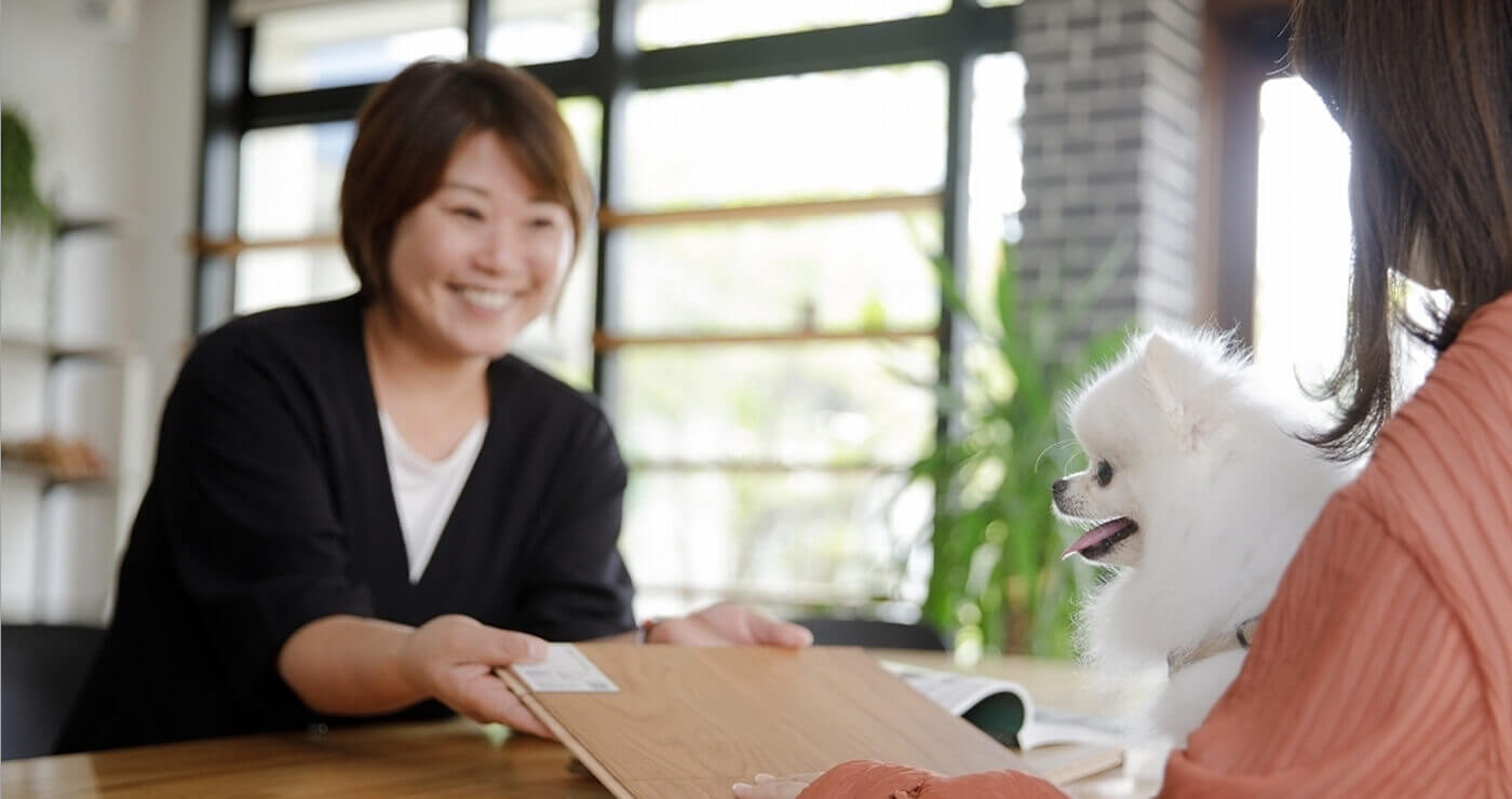 「ペットを抱える女性とスタッフ。サービスを説明している様子